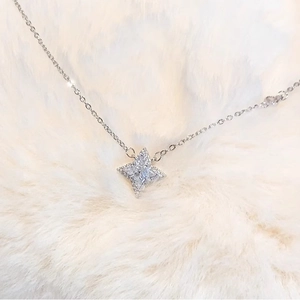 Macro detail of silver four-pointed star pendant with sparkling cubic zirconia on plush