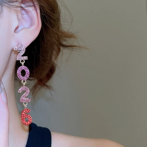 Détail de longues boucles d'oreilles 2026 avec strass dégradés roses et rouges sur modèle