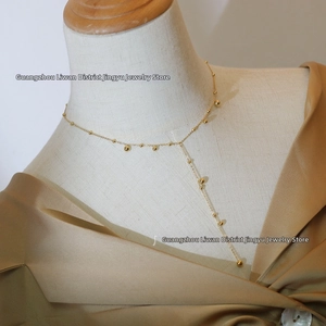 Detail of elegant 18K gold-plated Y-shaped tassel necklace featuring small beads on mannequin