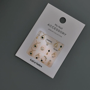 Détail de bijoux d'ongles dorés avec pierres émeraudes et strass en formes de gouttes