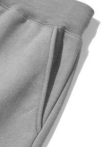 Close-up of grey fleece jogger pants showing ribbed drawstring waist and side pocket