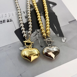 Gold and silver heart pendant necklaces with bead chains and toggle clasps on a magazine