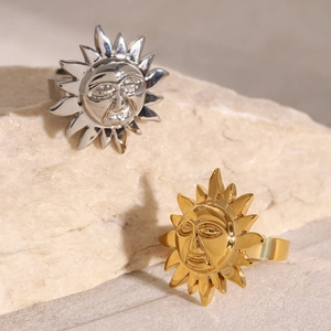 Exaggerated sun god face rings in gold and silver finish on a natural stone background