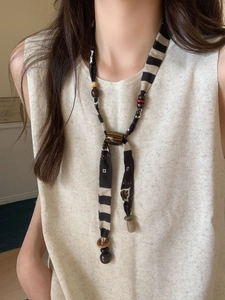 Detail of bohemian necklace with black and white fabric patterns and wooden beads