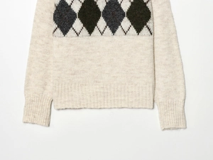 Detail of argyle knit sweater showing ribbed hem and textured wool blend fabric