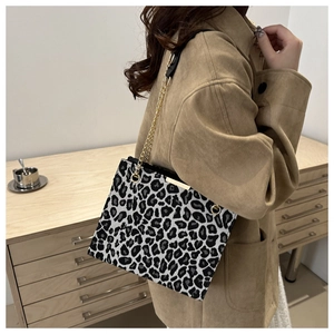 Détail du sac à bandoulière imprimé léopard avec chaîne dorée porté par un mannequin