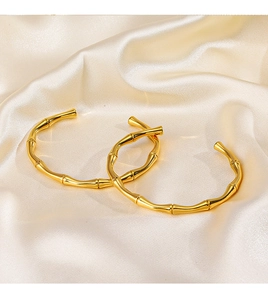Dettaglio di due bracciali d'oro in stile bambù su sfondo in tessuto di seta champagne