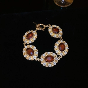 Detailed view of the amber gemstone bracelet with white enamel flowers on black velvet