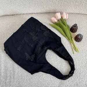Detail of black lace tote bag featuring 3D butterfly embroidery in a scenic layout