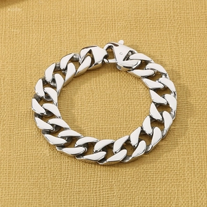 Detail of silver Cuban link bracelet with lobster clasp on a textured background