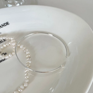 Minimalist S925 sterling silver open bangle with double beads on a white ceramic plate