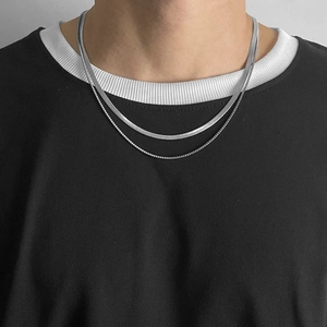 Close-up of double-layered silver snake chain and box chain necklace on black shirt