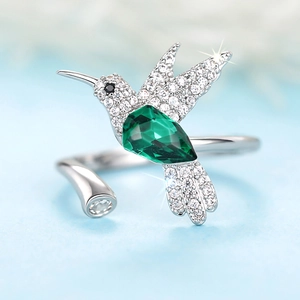 Detail macro-opname van een zilveren kolibrie ring met een fonkelende groene druppelsteen