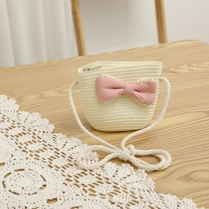 Close-up of children straw crossbody bag with pink polka dot bow and metal zipper