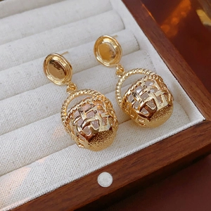 Close-up of vintage golden hollow basket earrings with faux pearl detail on velvet