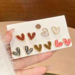 Close-up of heart-shaped pearl stud earrings set in five colorful resin styles