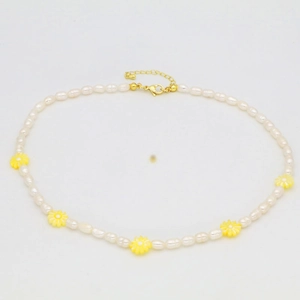 Close-up of freshwater pearl necklace featuring yellow daisy accents and golden clasp