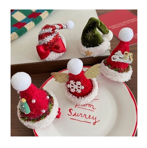 Détail de cinq mini chapeaux de Noël barrettes avec nœuds et paillettes sur plateau blanc