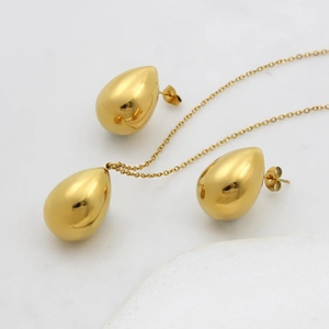 Detailed view of water drop pendant necklace and earrings set on marble surface