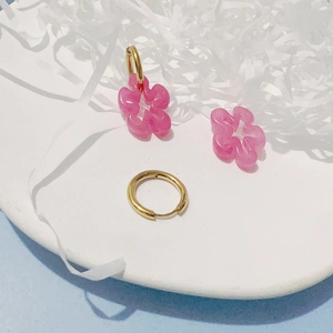 Vue détaillée des pendentifs fleurs en résine rose avec créoles dorées en or 18K