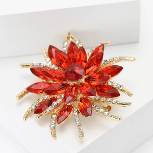 Macro detail of red marquise-cut gems and sparkling crystals on a golden flower brooch