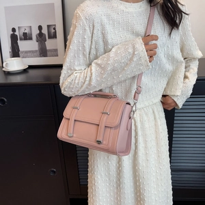 Pink PU leather crossbody bag with silver buckles shown on white dress model detail