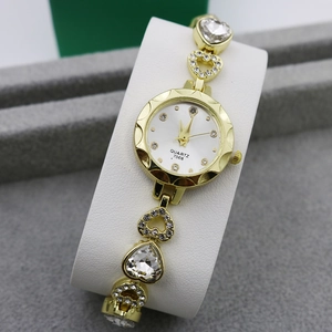 Detail of gold-tone quartz watch featuring rhinestone heart links and round white dial