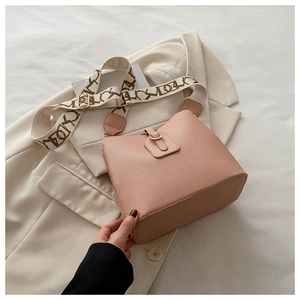 Close-up of pink pebbled leather bucket bag with gold buckle and wide patterned strap