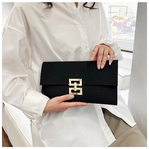 Detail of black crocodile texture envelope clutch bag with gold geometric metal lock