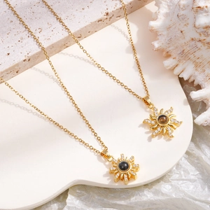 Golden sun flower projection necklace with zircon petals and dark stone core on stone