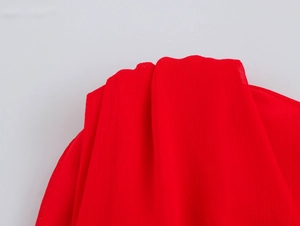 Close-up of red chiffon fabric showing fine wrinkled texture and translucent grain