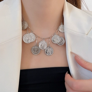 Close-up of multi-layered silver coin pendant necklace with detailed portrait reliefs