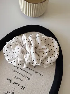 Close-up of pleated white chiffon polka dot hair scrunchie on a decorative tray