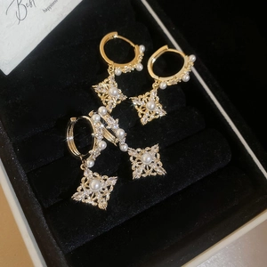 Close-up of 18K gold-plated diamond rhumbus earrings with pearls in black jewelry box