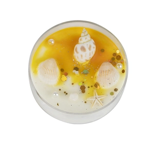 Top view of sea shell scented candle with starfish pearls and golden glitter in glass