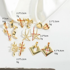 Collection of golden alloy earrings with heart and star designs on white silk background