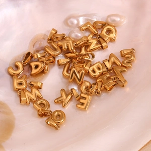 Macro view of 18K gold plated bubble initial charms on elegant pearl and shell background