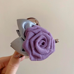 Détail d'une rose en satin violet et de feuilles grises sur une pince à cheveux marron