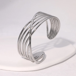 Detailed view of silver minimalist crisscross metal cuff bracelet on white display stand