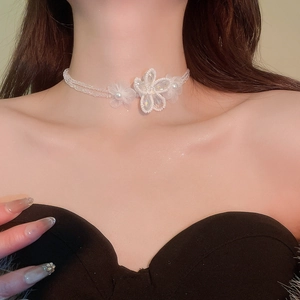 Detailed view of an elegant white floral choker with crystals and pearls on a model