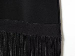 Détail de robe noire avec bande en satin et longues franges élégantes au bas
