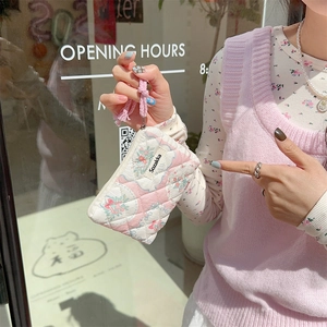 Detailed view of quilted floral coin purse with pink handle and brand label