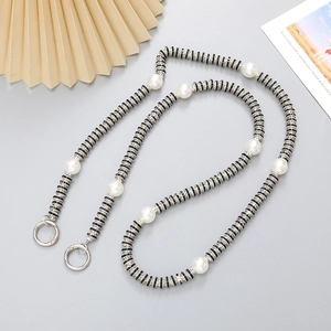 Luxury black and silver crossbody phone chain with pearls and rhinestones on a desk