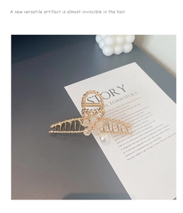Detail of gold floral hair claw clip with rhinestones and hanging pearl decoration