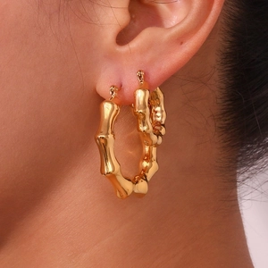 Polished gold-plated stainless steel geometric bamboo hoop earrings on female model