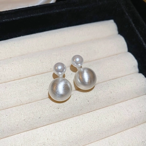 Close-up of silver double pearl stud earrings with matte and glossy finish on jewelry box