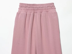 Détail d'un pantalon en tricot rose avec taille haute élastique plissée et texture gaufrée