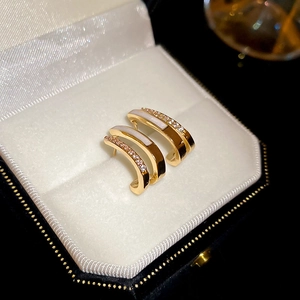 Close-up of golden double-layer C-shaped earrings with white shell and zircon in gift box