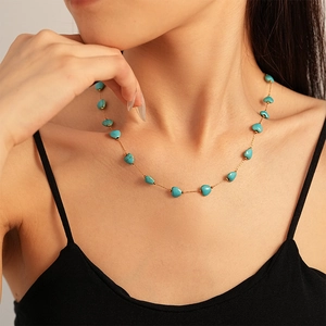 Gros plan sur un collier doré orné de perles bleues en forme de cœur turquoise