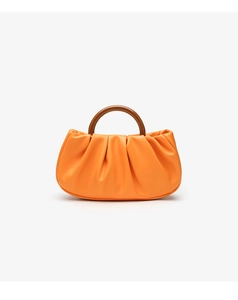 Detailed view of an orange ruched dumpling bag with a circular wooden handle